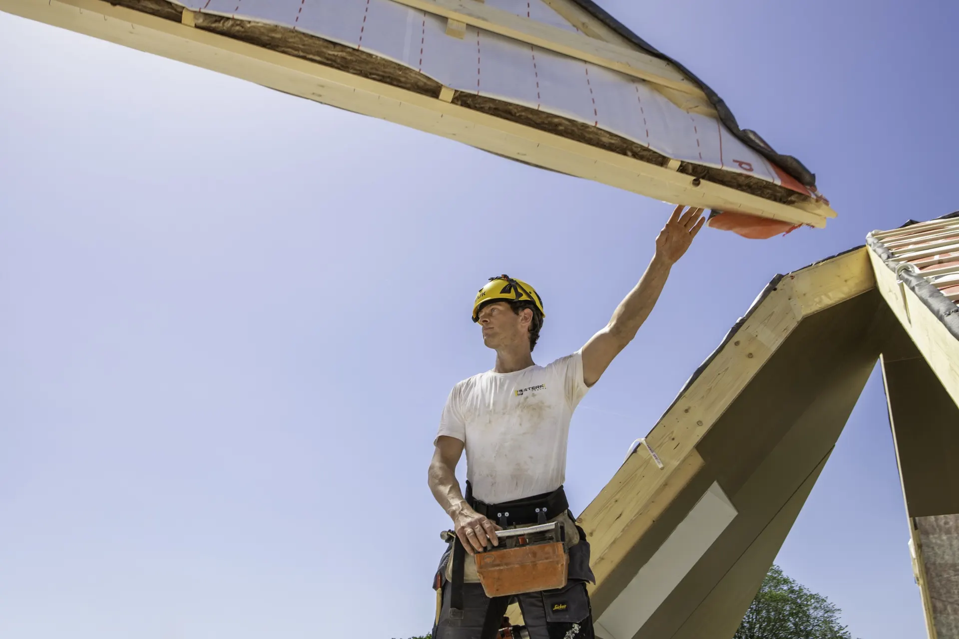 Monteur van Sterkk Prefab reikt naar een dakelement